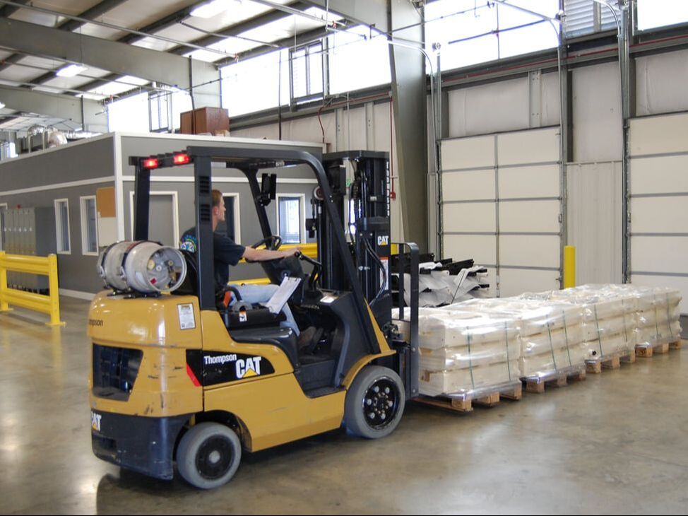 Forklift moving packaged, coated parts for shipping at ICS